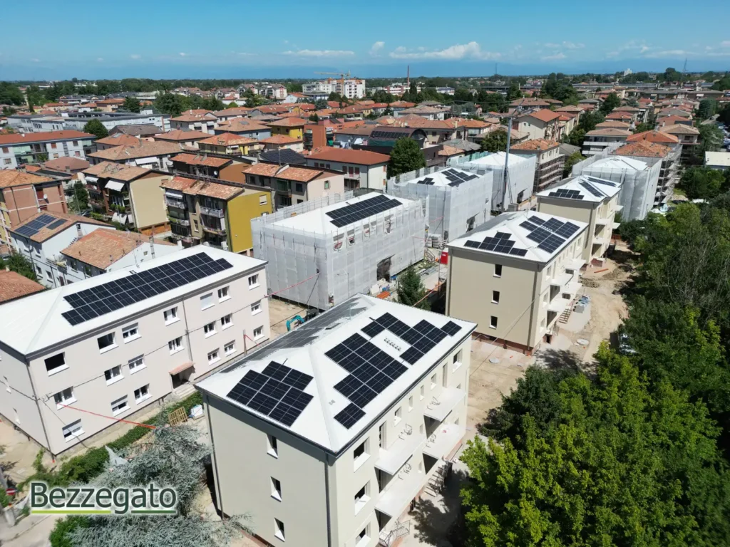 Aerial view of a residential neighborhood with several apartment buildings and solar panels on the rooftops, stretching to the horizon.